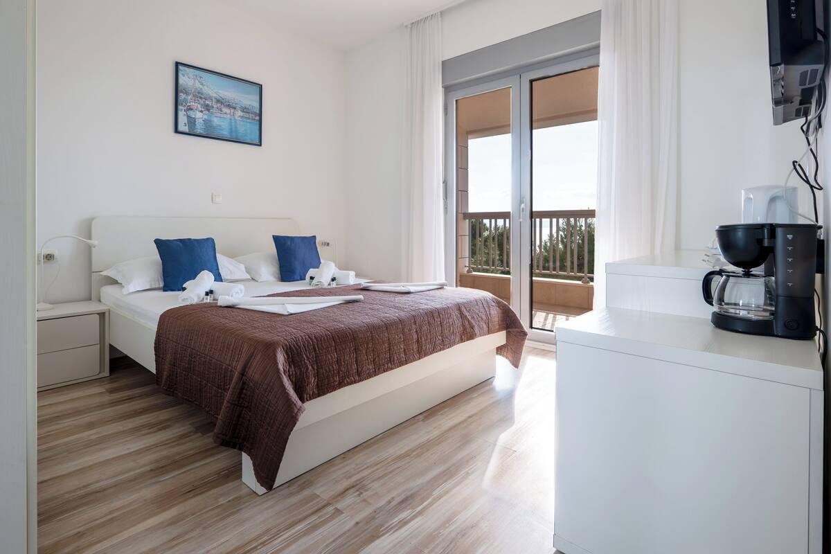 A hotel room with a bed, a coffee maker, and a balcony with a view.