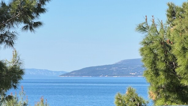 A balcony with a view of the sea, a bottle of wine, and a glass. - Pansion Simic (Makarska)