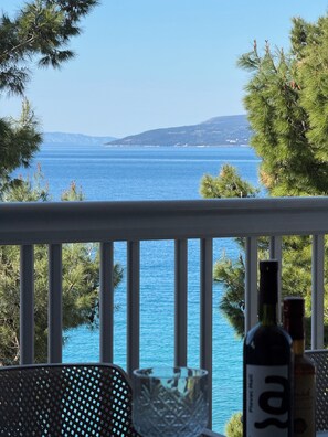 A balcony with a view of the sea, a bottle of wine, and a glass. - Pansion Simic (Makarska)