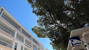 A modern building with multiple balconies, a covered walkway, and a sign for a business named "LAVATZA". - Pansion Simic (Makarska)