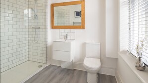 Ein modernes Badezimmer mit einer Duschkabine, einem weißen Waschbecken und einer Toilette.