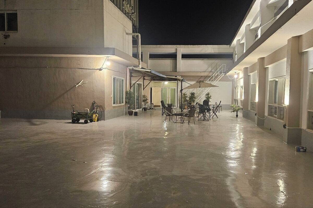 A spacious outdoor area with a concrete floor, multiple seating arrangements, and potted plants.