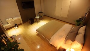 A hotel room with a large bed, a TV mounted on the wall, a small table with a chair, and a closet with sliding doors. - RIVER HOTEL NAMWON (Namwon)