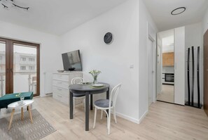 A modern room with a dining table, chairs, a clock, and a view of the outside.