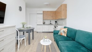 A compact living space with a kitchenette, a dining area, and a green sofa.