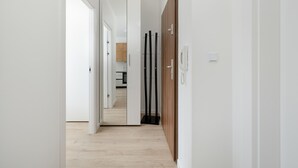 A hallway with a wooden door, a telephone, and a mirror on the wall.