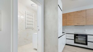 A modern kitchen with a built-in oven, wooden cabinets, and a marble backsplash.