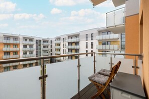 Ein Balkon mit Stuhl, Geländer und Blick auf mehrstöckige Gebäude.