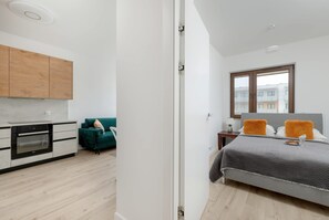 A modern apartment with a kitchen, a dining area, and a bedroom with a large bed and a window.