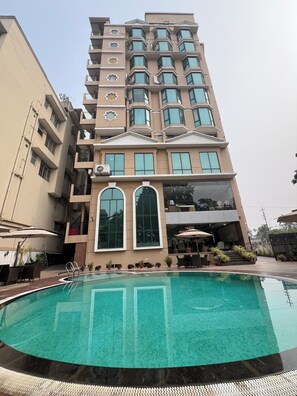 Un hotel a più piani con una piscina in primo piano.