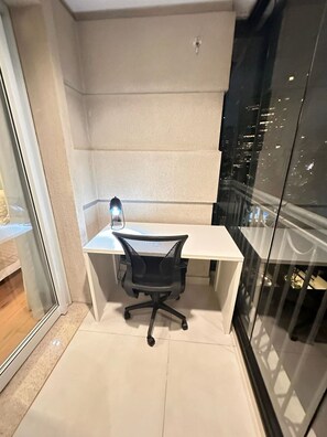 A modern office space with a white desk, black office chair, and a glass partition. - J Come Style Surprising 1 Bed in Vila Olimpia (São Paulo)