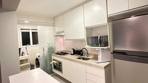 A modern kitchen with white cabinets, stainless steel appliances, and a central island. - J Come Style Surprising 1 Bed in Vila Olimpia (São Paulo)