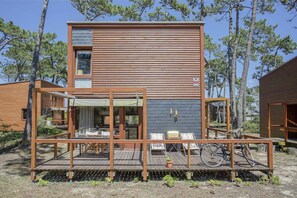 A modern wooden cabin with a deck, outdoor seating, and a bicycle. - Liiiving in Ofir - Seaside Pool Bungalow (Esposende)