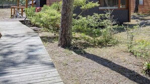 A modern building with a wooden deck, surrounded by trees and a clear sky.