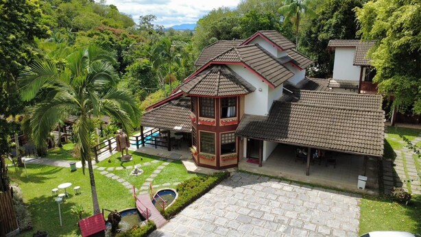 Ein traditionelles Haus mit Ziegeldach, ein kleiner Garten mit Palmen und ein Steinweg, der zu einem Pool führt.