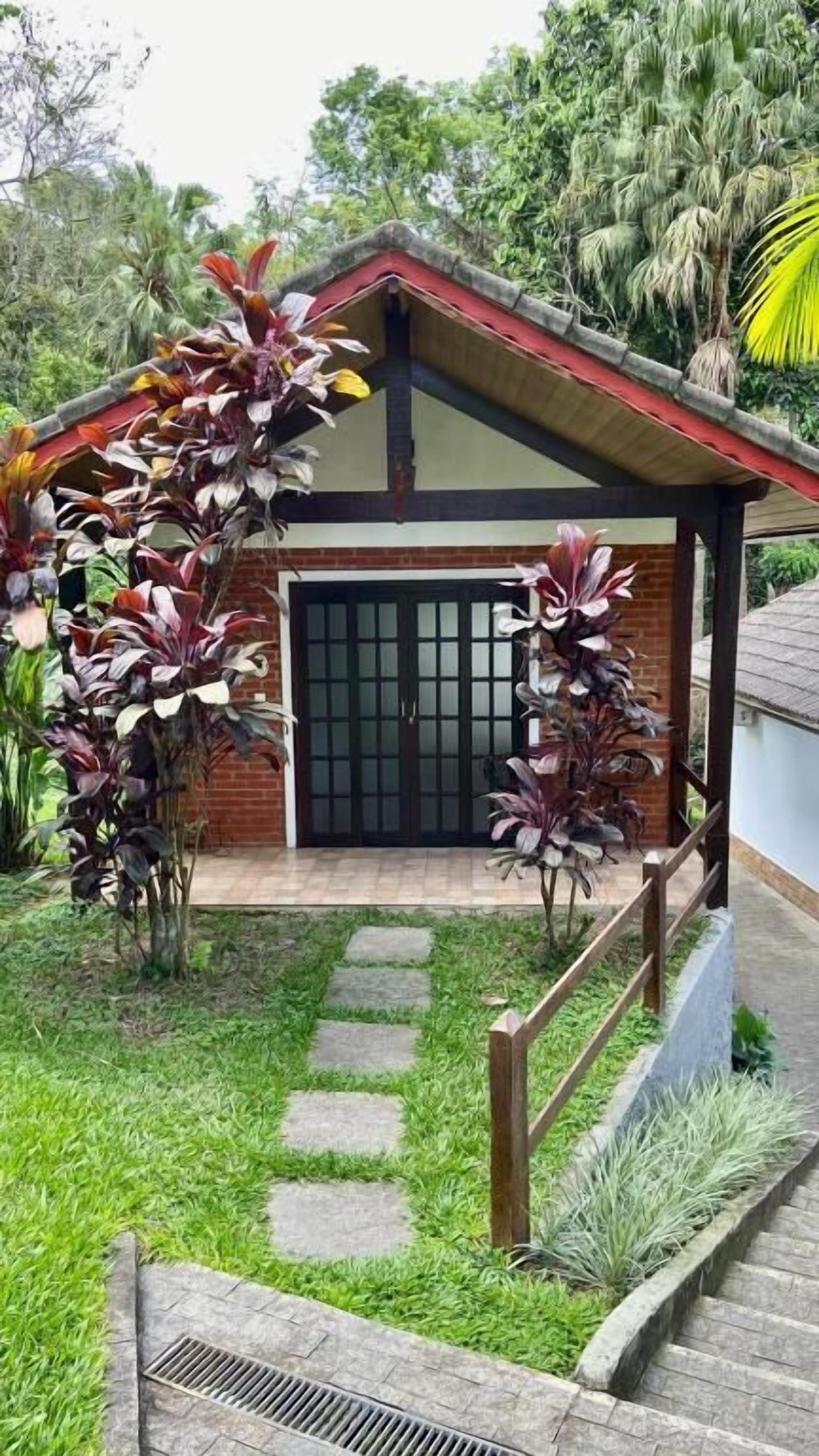 Una casa con fachada de ladrillo, un porche de madera y un camino de piedra que conduce a una puerta negra.