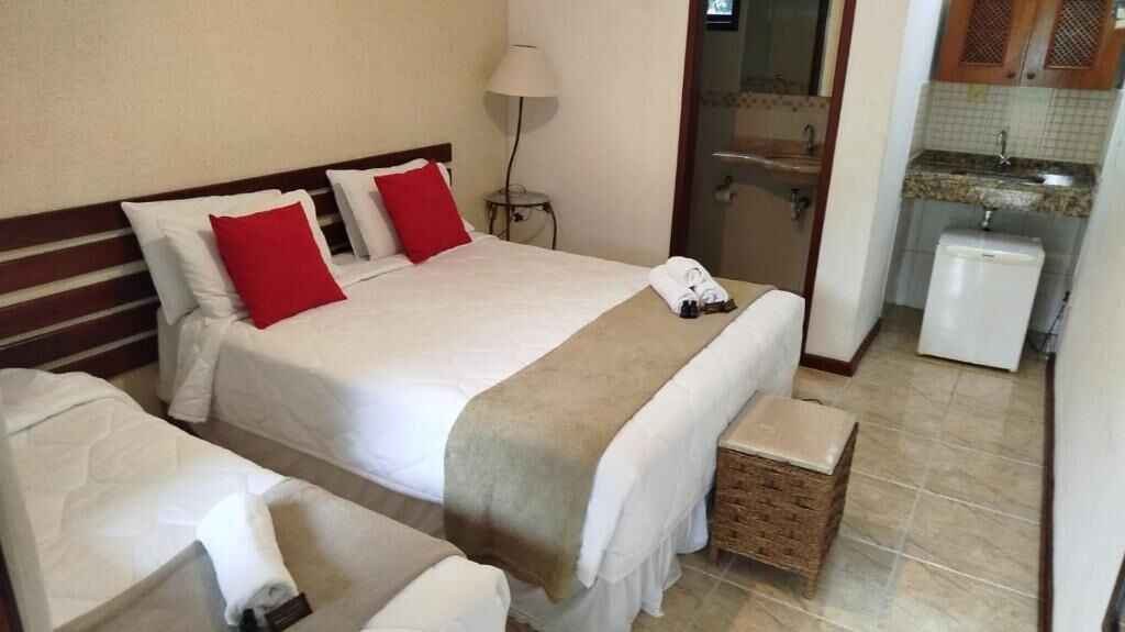A hotel room with two beds, a small kitchenette, and a bathroom visible through an open door.