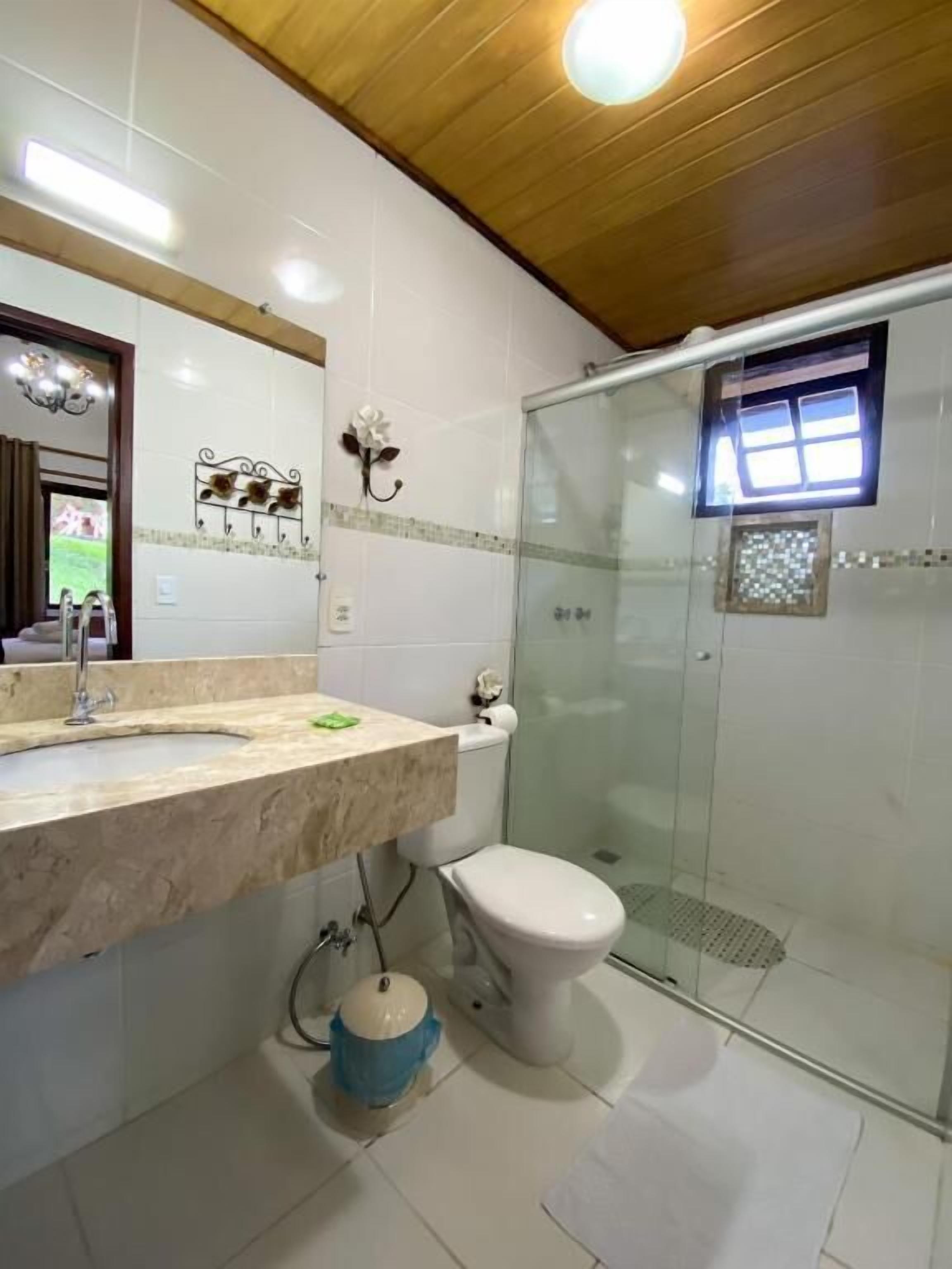 A bathroom with a marble sink, a toilet, and a glass-enclosed shower.