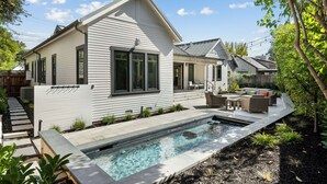 Ett modernt hus med en swimmingpool, en uteplats med utemöbler och en välskött trädgård.
