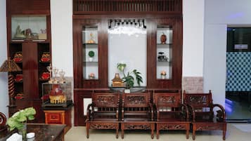 A traditional wooden furniture set with intricate carvings, a glass display cabinet with decorative items, and a potted plant.