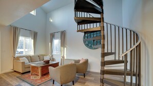 Un salon spacieux avec un escalier moderne, un ensemble de canapés et une table basse.