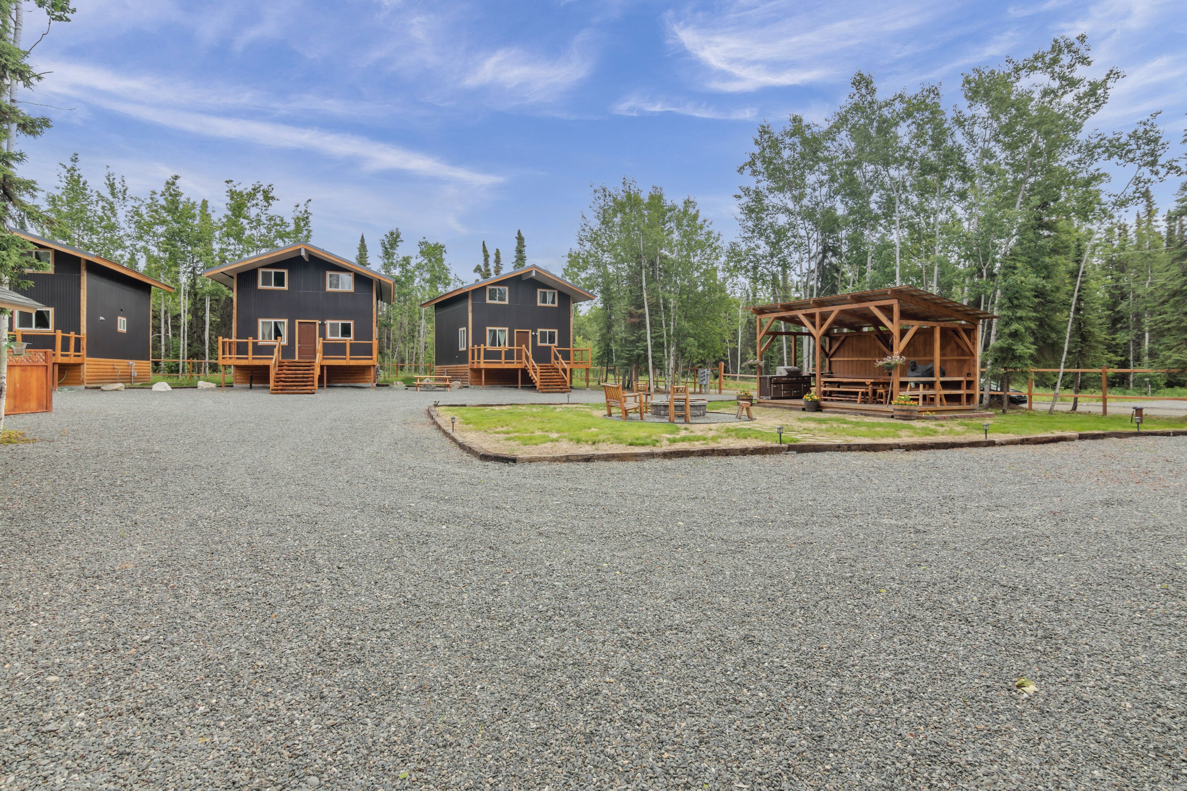 A resort with three cabins, each with a wooden deck and a small outdoor seating area.