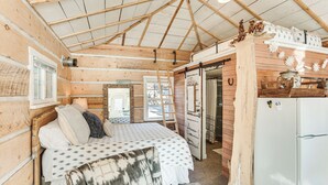 A rustic wooden cabin interior with a bed, a refrigerator, and a wooden door. - 4 Mi to Main Street: Riverfront Minnesota Cabin (Elk River)