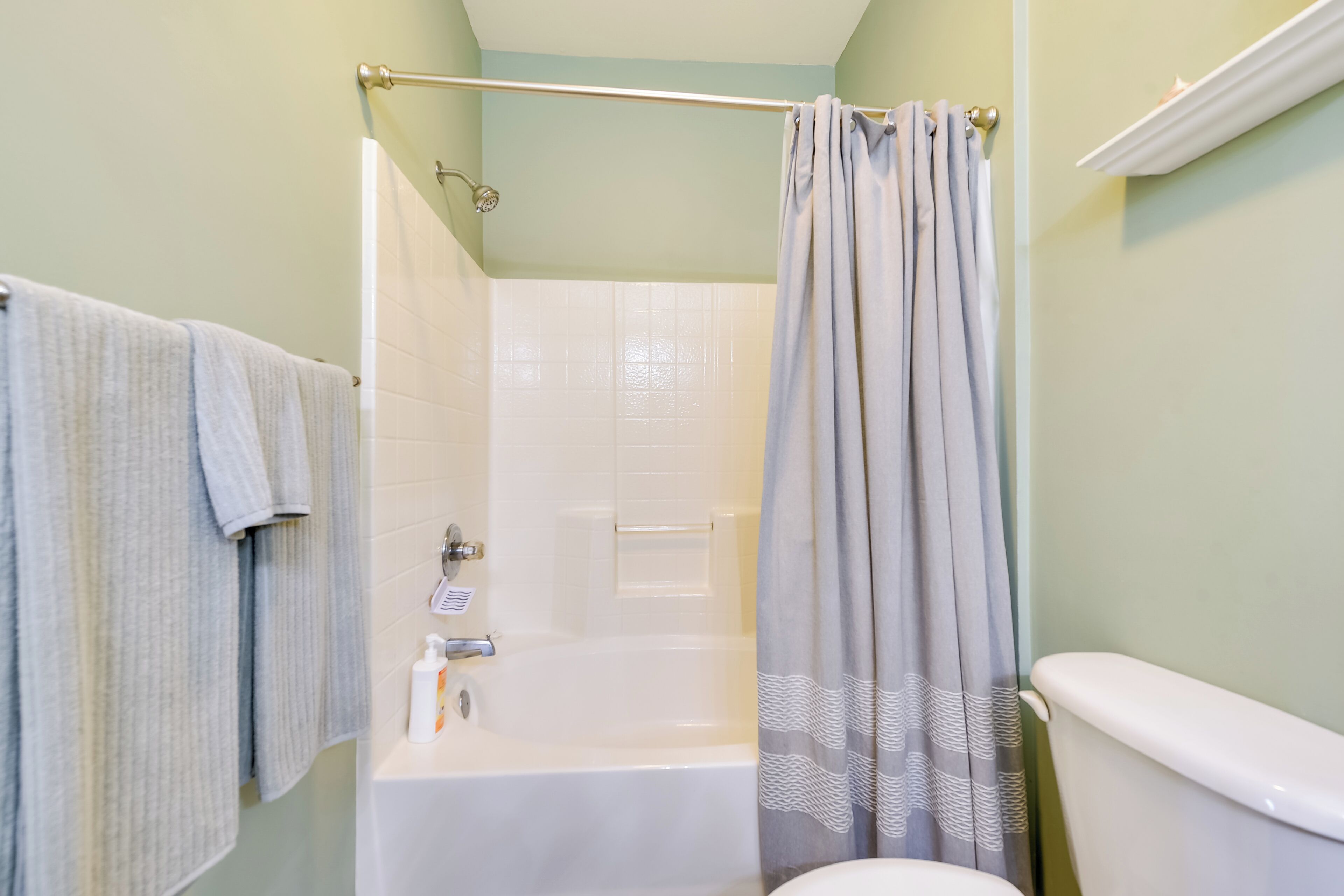 A bathroom with a bathtub, toilet, and shower curtain.