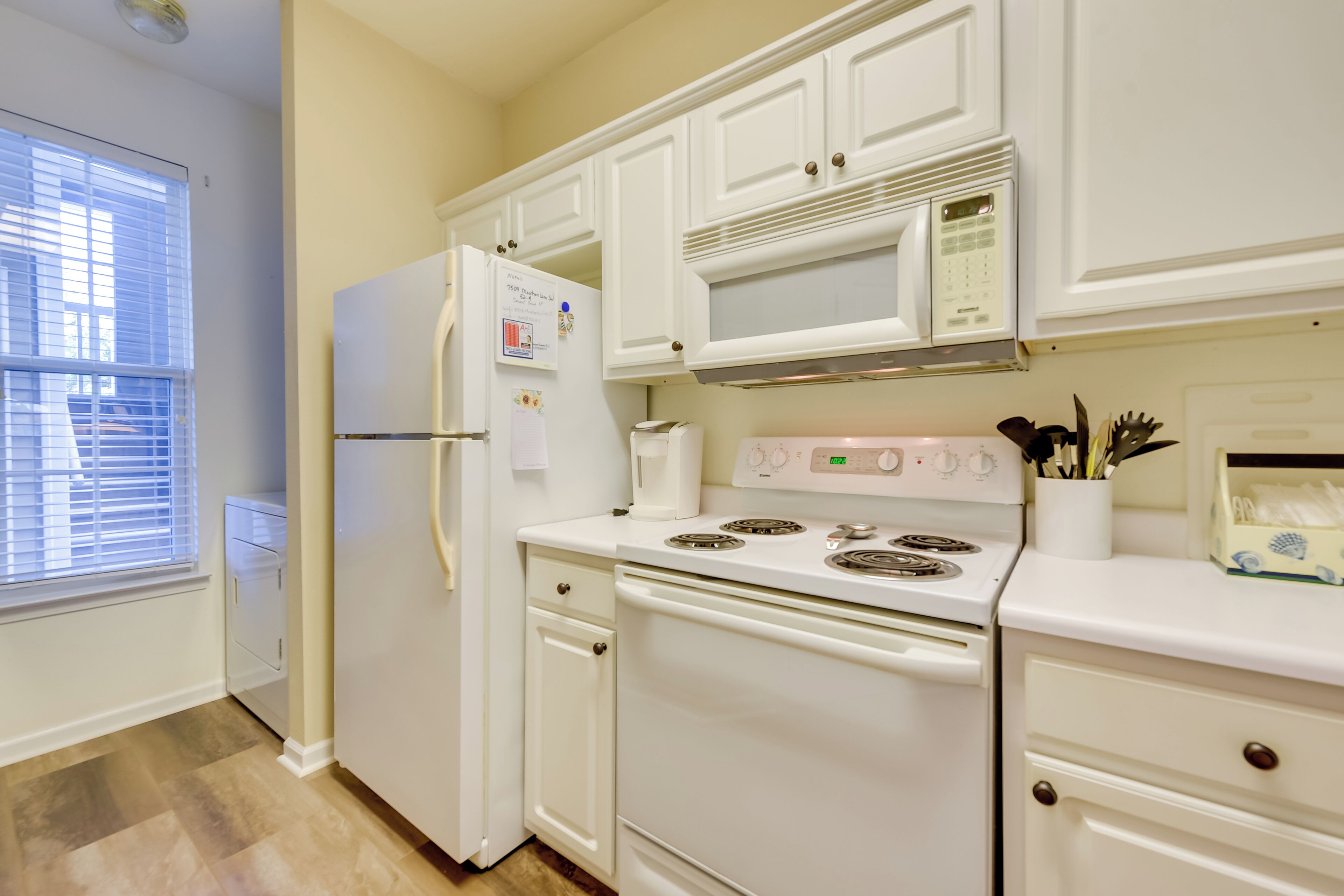 A kitchen with white cabinets, a refrigerator, a microwave, and a stove.