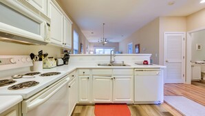 A modern kitchen with white cabinetry, a built-in stove, and a large island with a sink. - Pond Views & Community Perks: Sunset Beach Condo! (Sunset Beach)