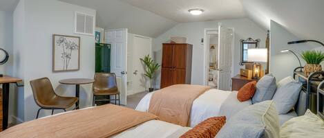 Une chambre d’hôtel avec deux lits, un bureau, une chaise, une petite table et une armoire.