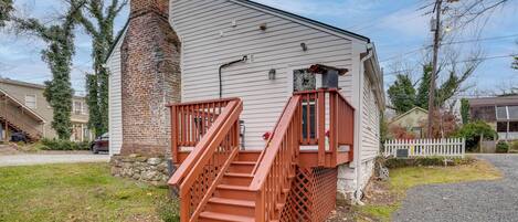 Une maison à deux étages avec une cheminée en briques, un escalier en bois et une clôture blanche en piquets.