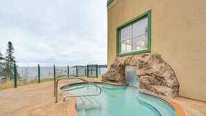 Piscina exterior com arco de pedra, vista para o mar e zona de estar ao ar livre.