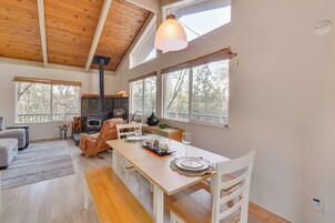 A spacious dining area with a wooden table set for four, white chairs, and a large window providing natural light.