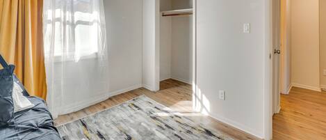 A room with a bed, a window with curtains, a closet, and a wooden floor.