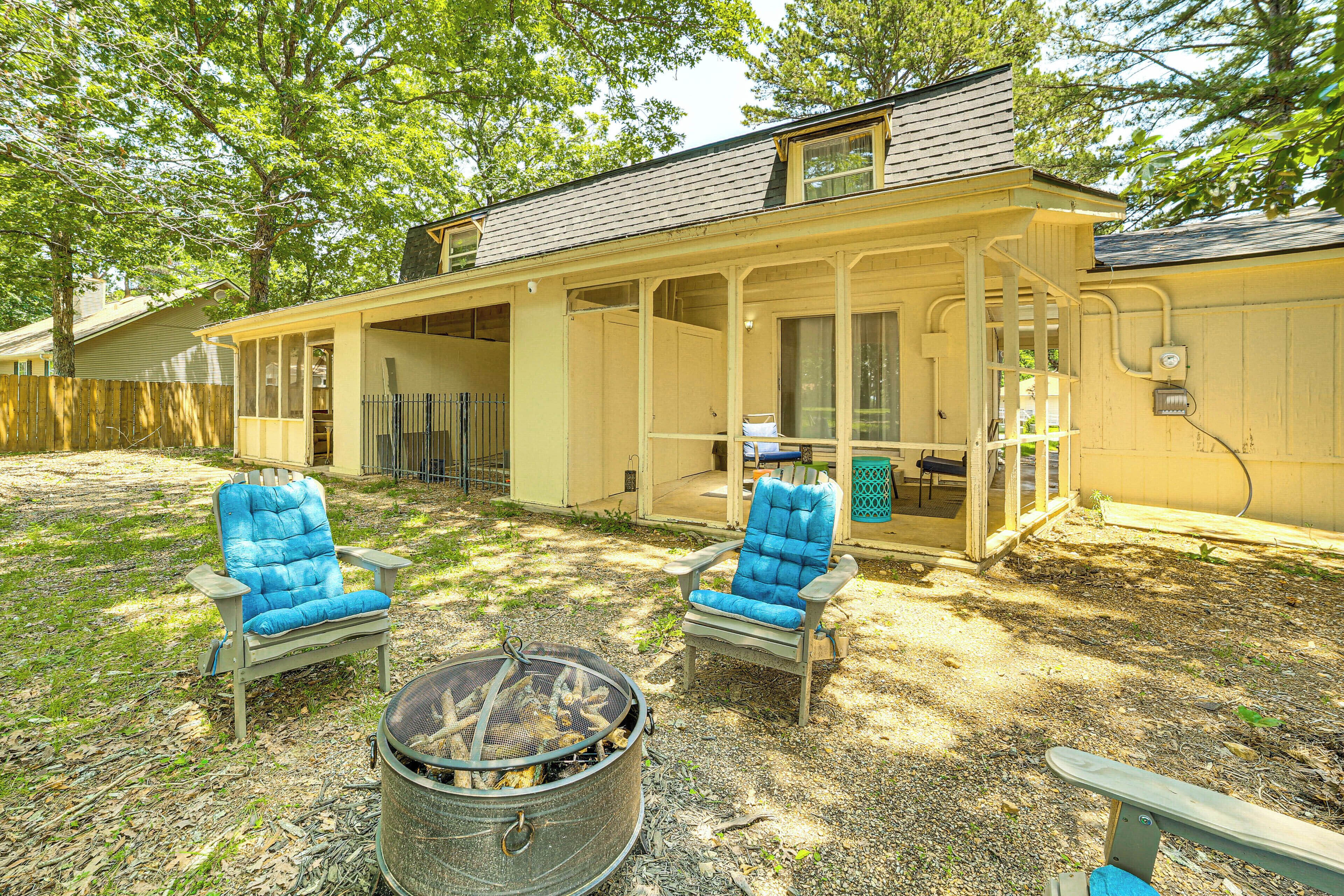 Ein überdachter Patio-Bereich mit zwei blauen Sitzmöbeln und einem Feuerkorb aus Metall.