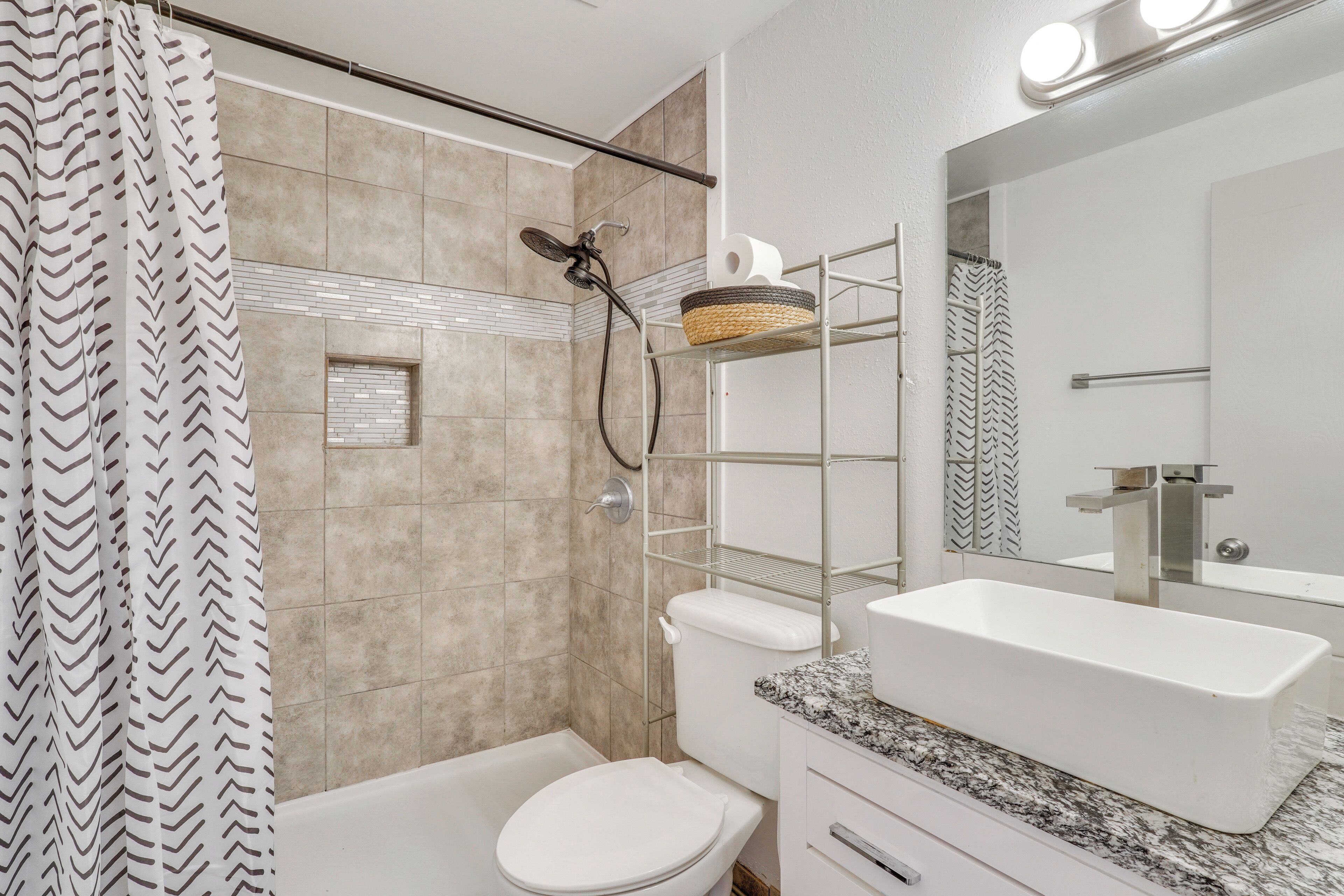 Un baño con ducha, inodoro y un lavamanos grande.