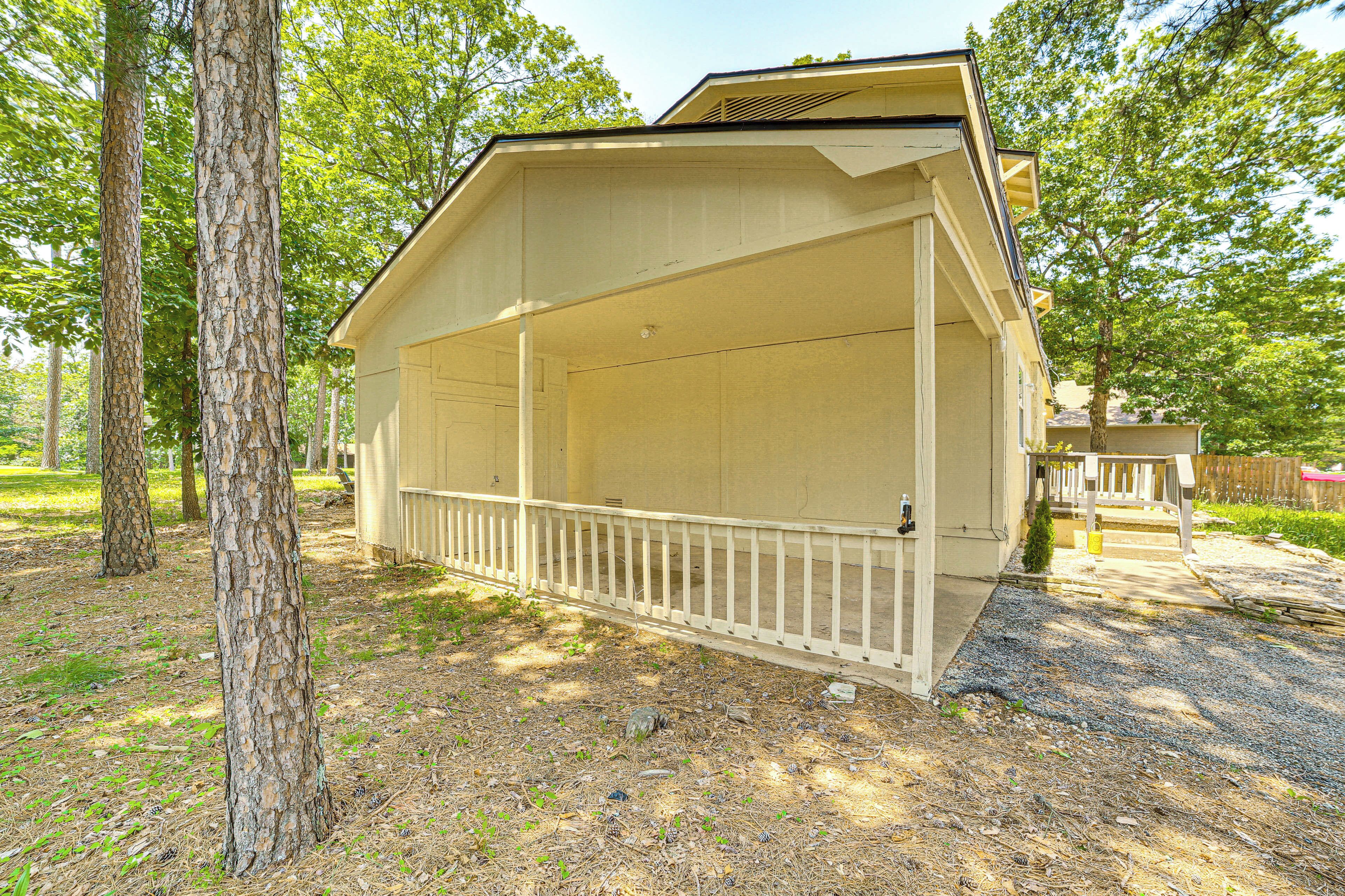 A covered outdoor area with a white railing, surrounded by trees.
