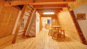 Un interno in legno con una scala, un'area pranzo con sgabelli e una sveglia appesa al muro.