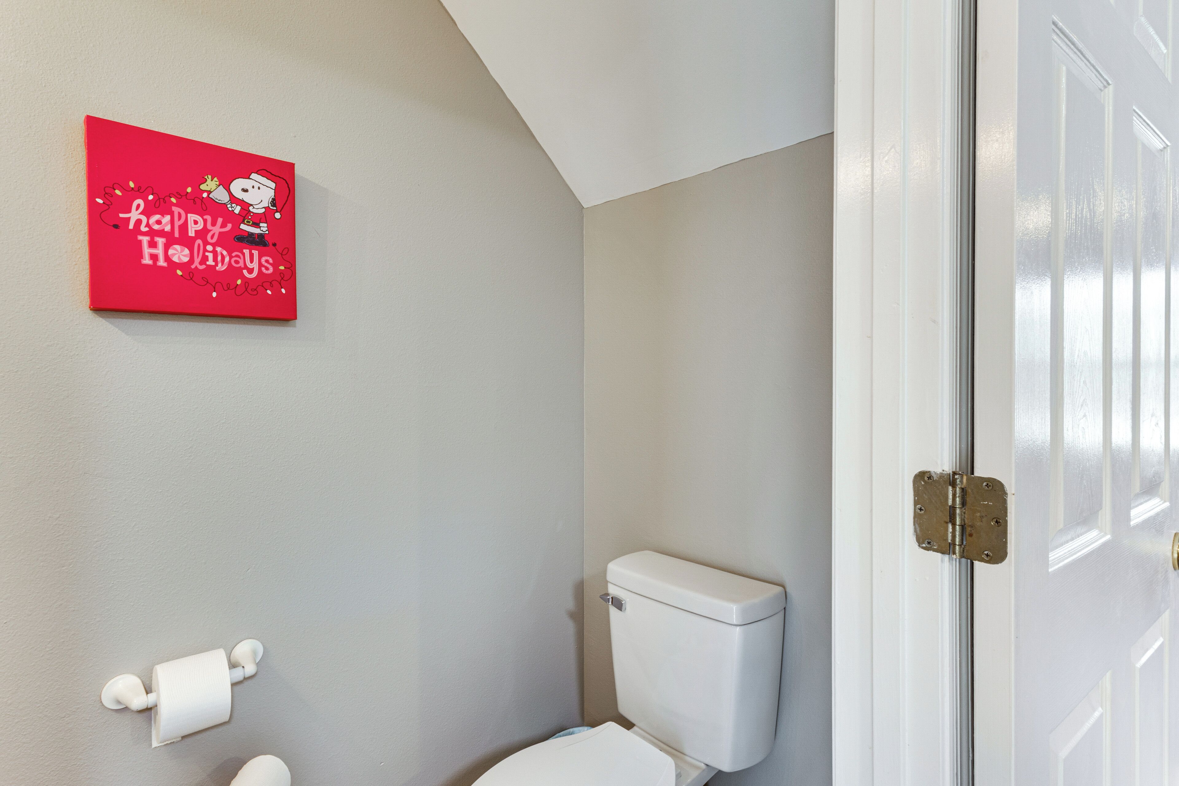 Et badeværelse med toilet, toiletpapir og en rød, festlig dekoration på væggen.