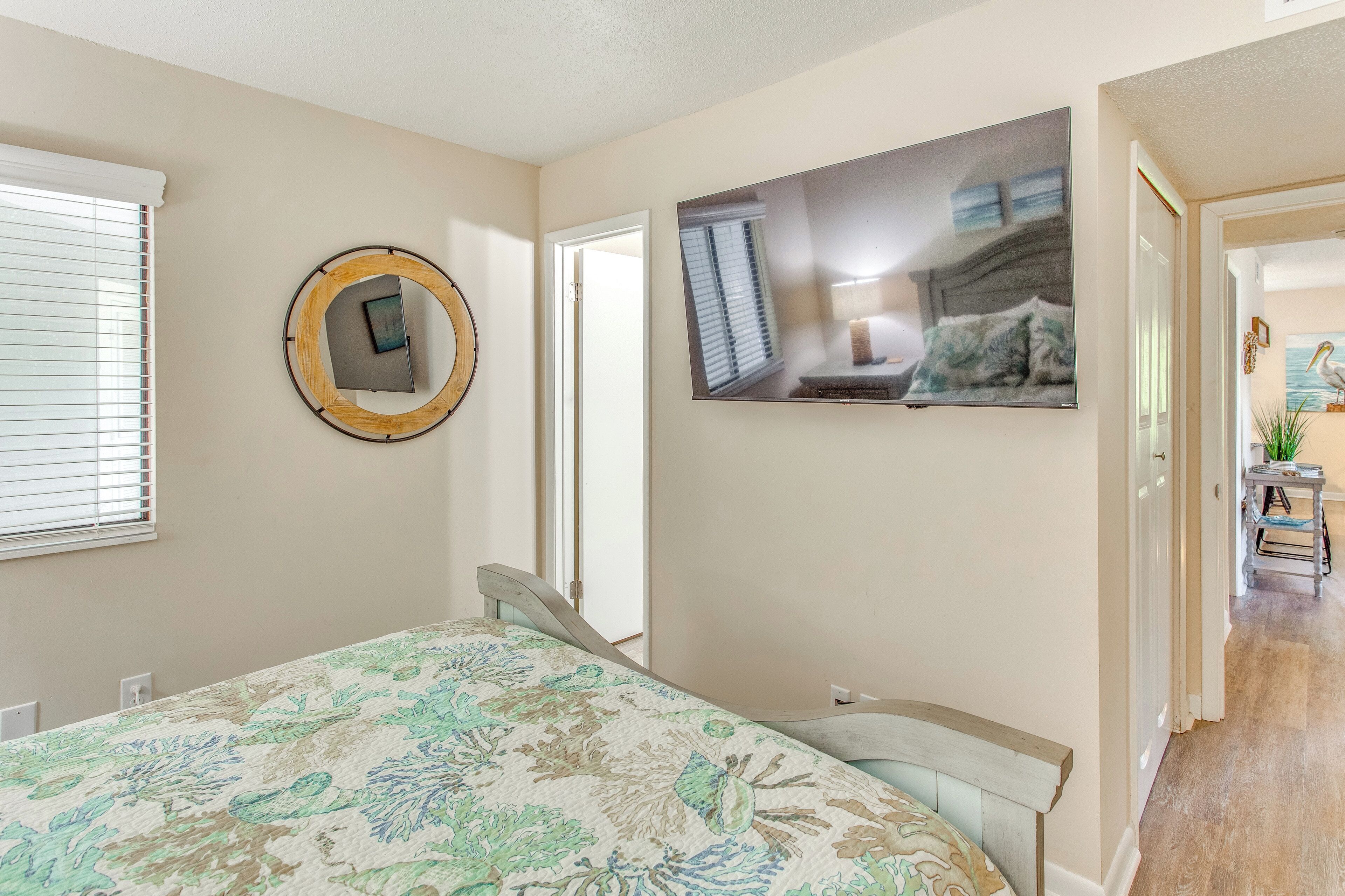 A bedroom with a bed, a round mirror, and a painting on the wall.
