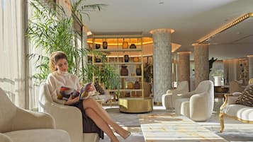 A well-lit, spacious lobby with a seating area, a large plant, and a bookshelf filled with books and decorative items.