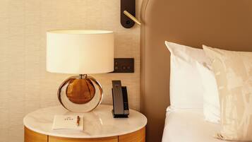 Une chambre d’hôtel avec un lit, une table de chevet avec une lampe, une télécommande et une carte posée sur la table.