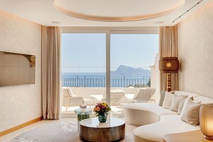 Une chambre d’hôtel moderne avec balcon, des meubles blancs et un grand téléviseur.