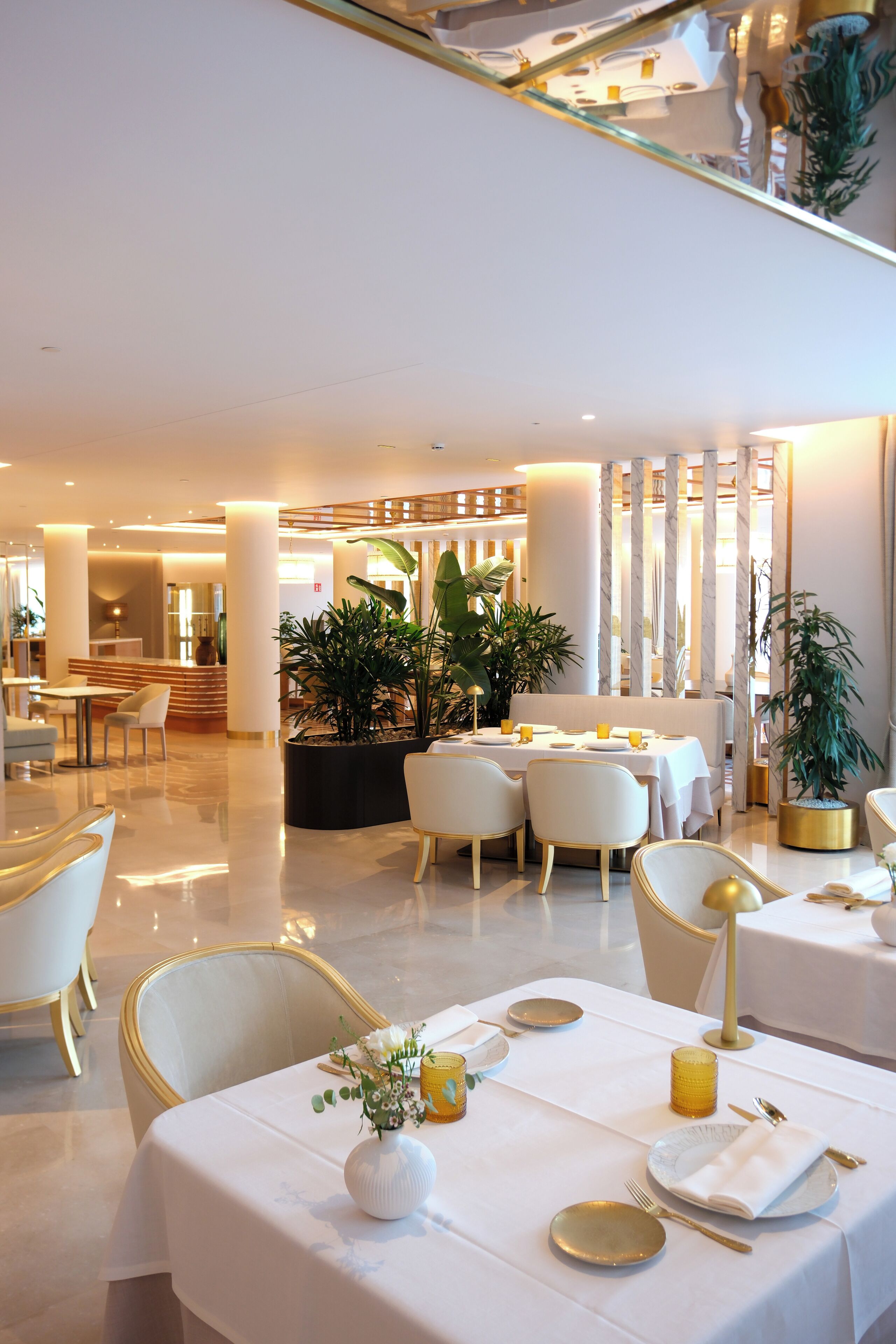 A modern hotel lobby with a reception desk, seating area, and decorative plants.