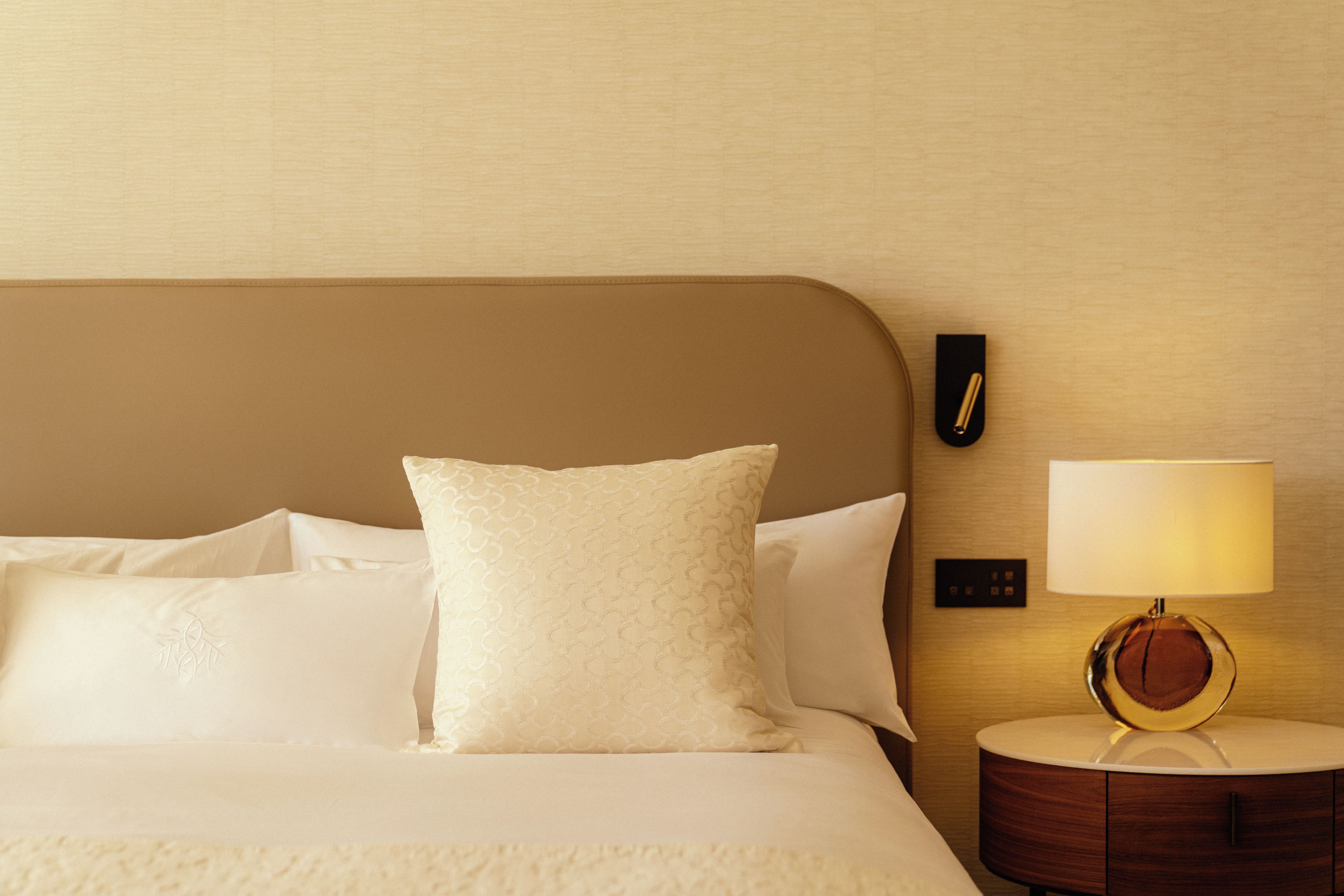 A neatly made bed with white linens and a single decorative pillow.
