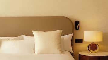A neatly made bed with white linens and a single decorative pillow.