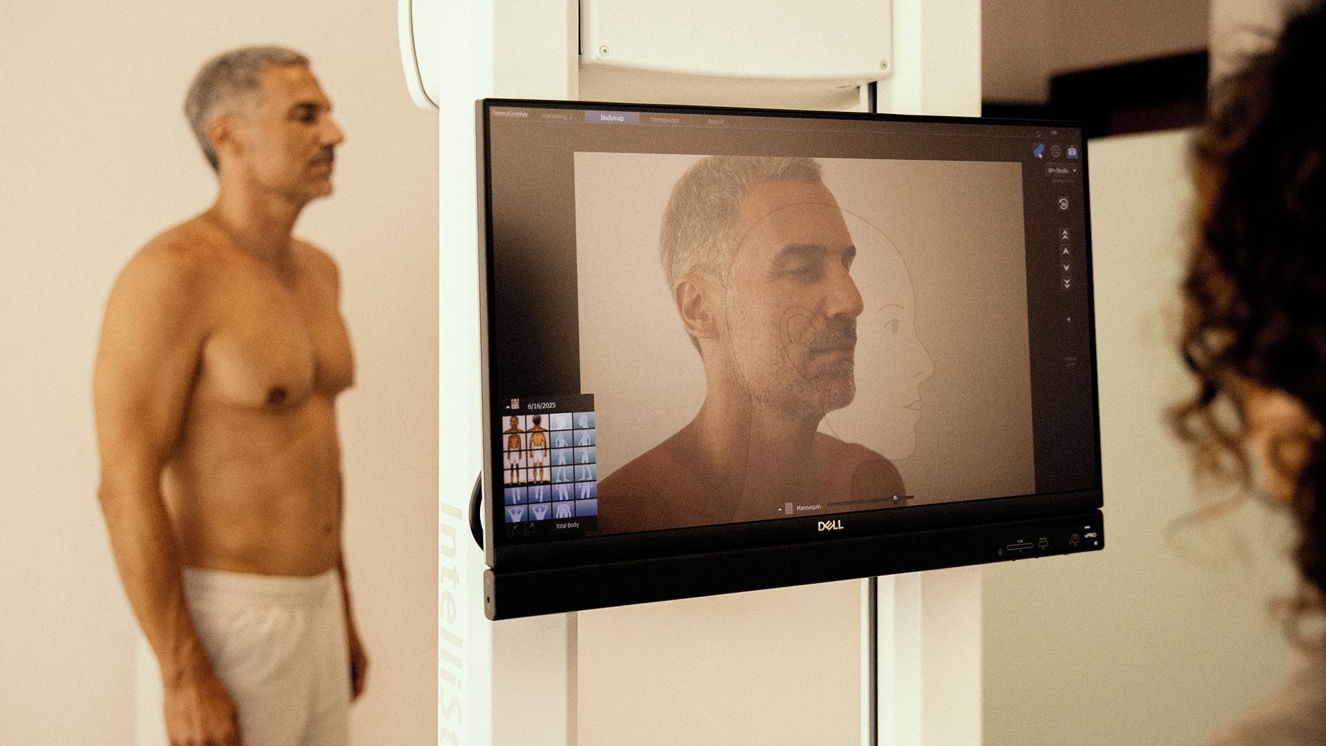 Una persona dret davant d'un monitor d'ordinador que mostra una imatge d'exploració corporal.