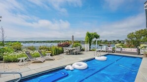 A swimming pool with lounge chairs and a view of the water.