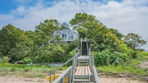 A wooden staircase leading to a house surrounded by dense greenery.